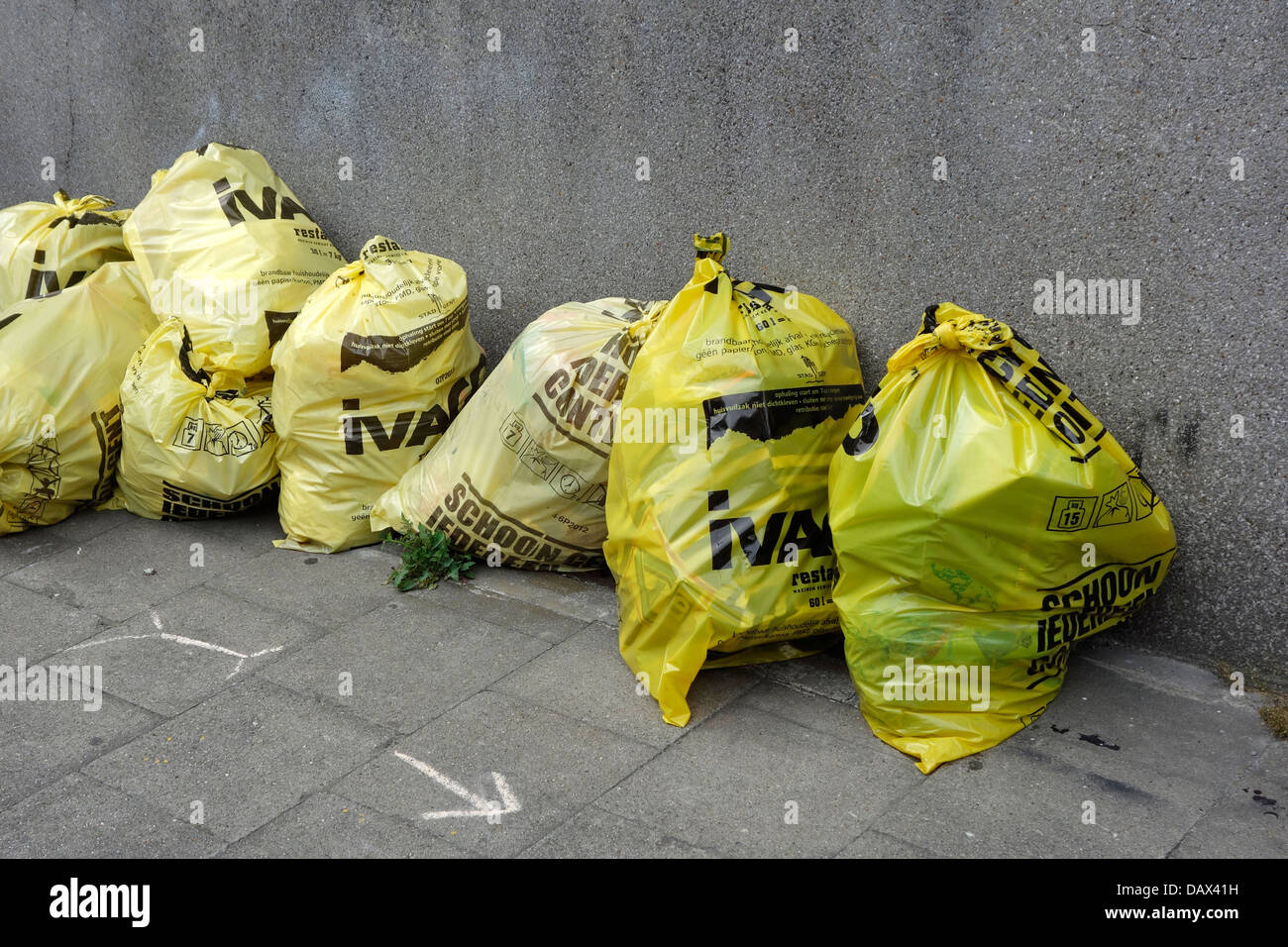 Sacchi spazzatura / cestino sacchetto con i rifiuti domestici sul marciapiede davanti alla casa in via della città Foto Stock