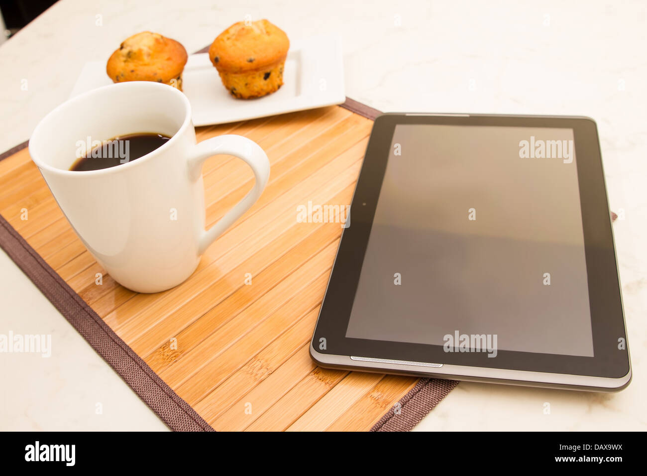 La vaniglia con scaglie di cioccolato muffin con una tazza di caffè nel frattempo usando il tablet. Foto Stock