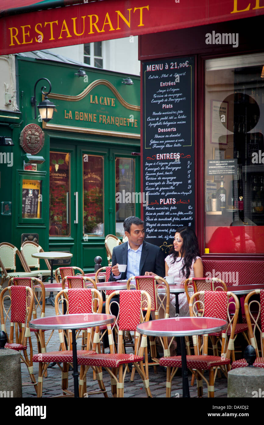 Giovane gode di tazza di caffè al cafè sul marciapiede in Montmartre, Parigi Francia Foto Stock
