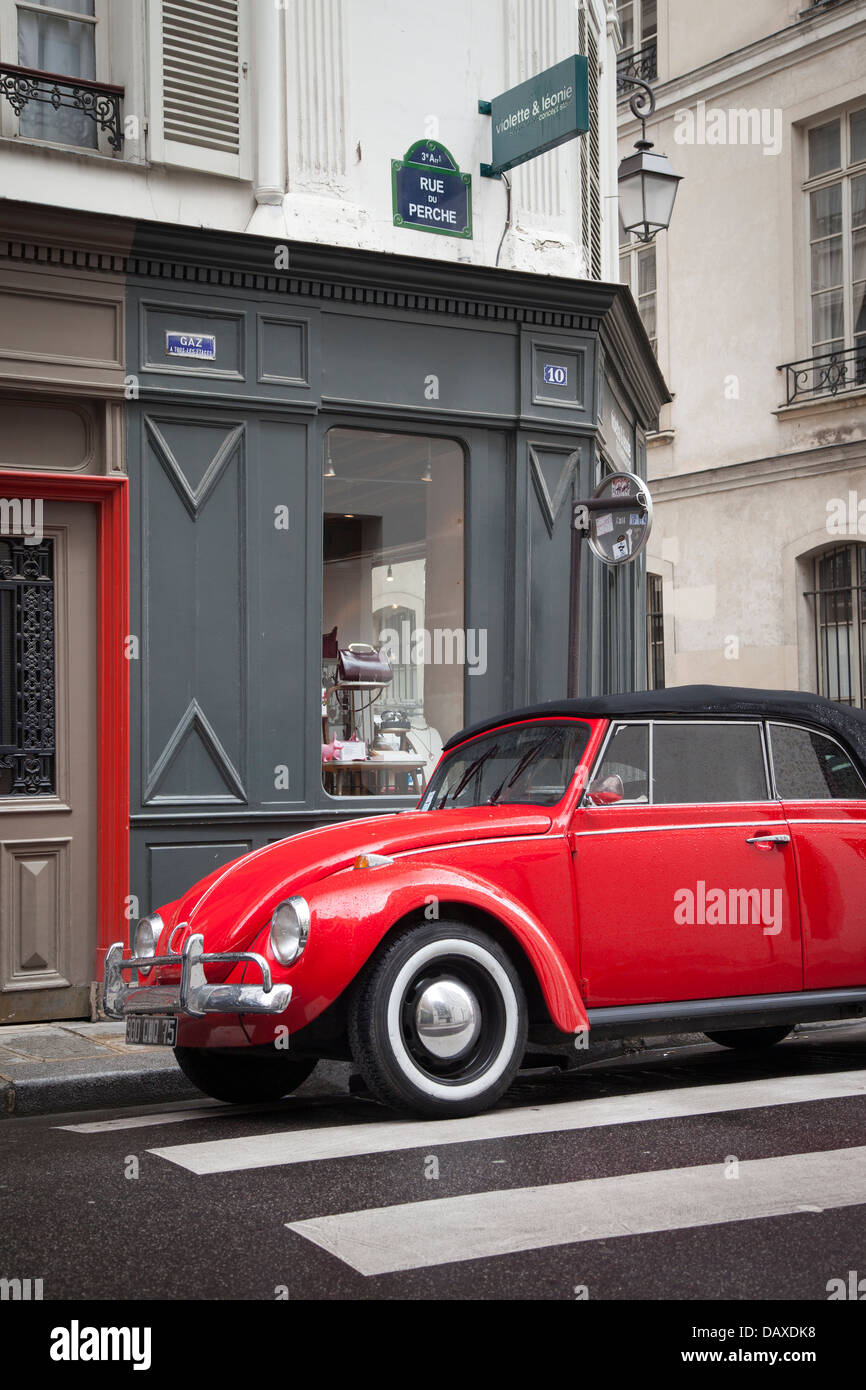 Red Volkswagen maggiolino parcheggiato di fronte alla spedizione shop nel quartiere del Marais, Parigi Francia Foto Stock