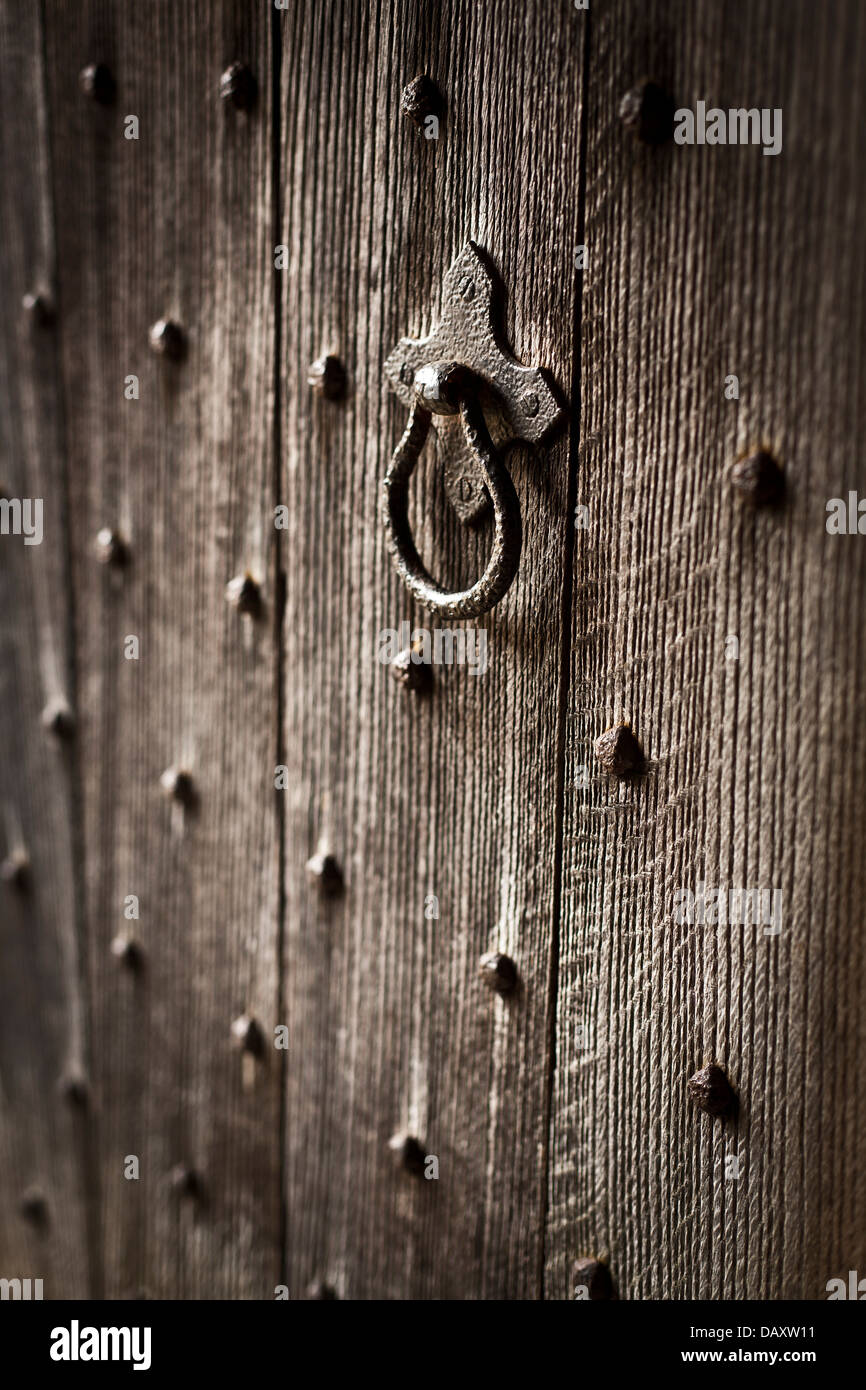 Close-up di un'antica porta di legno con metallo borchie e maniglia. Foto Stock