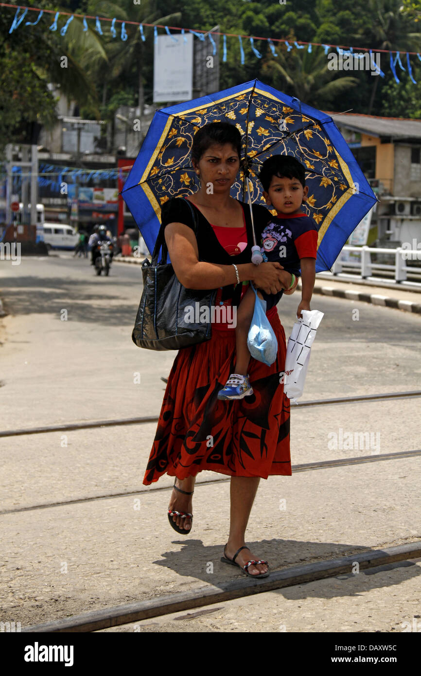 Donna con bambino & ombrello PERADENIYA SRI LANKA 12 Marzo 2013 Foto Stock