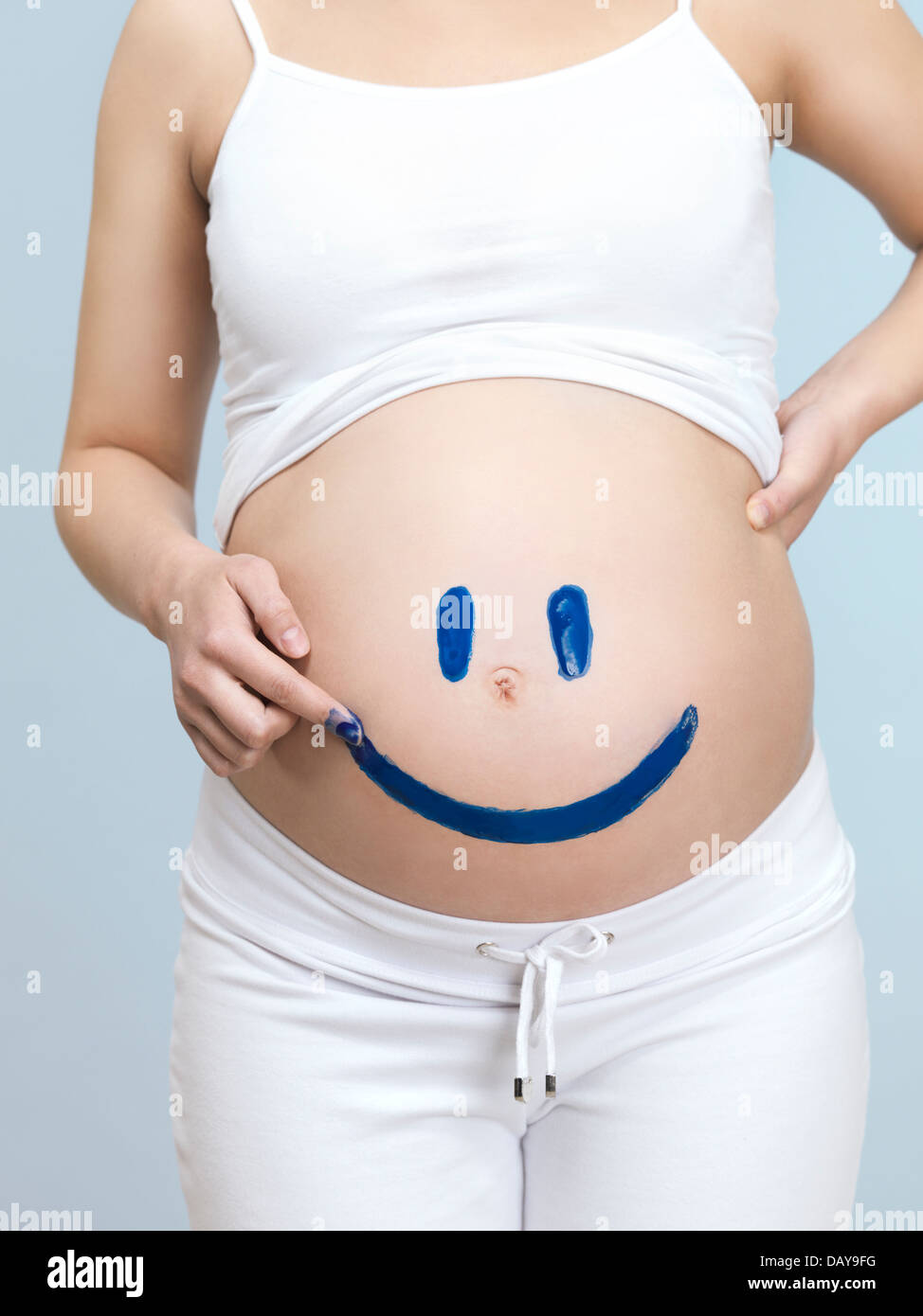 Donna incinta il disegno di una faccina felice faccia sul suo ventre Foto Stock