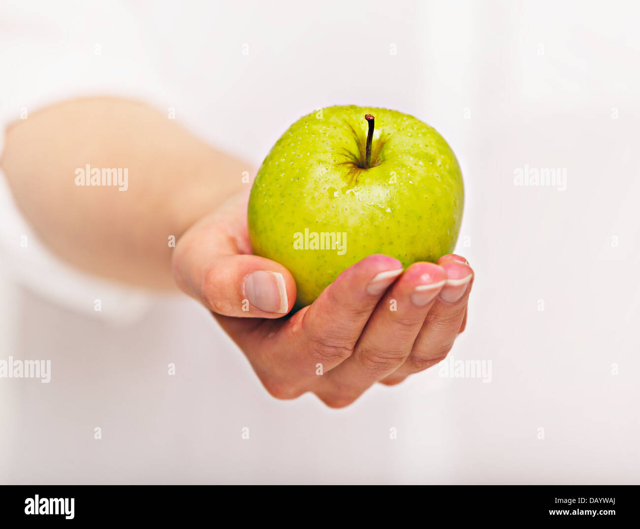 Donna di mano dando una mela verde Foto Stock