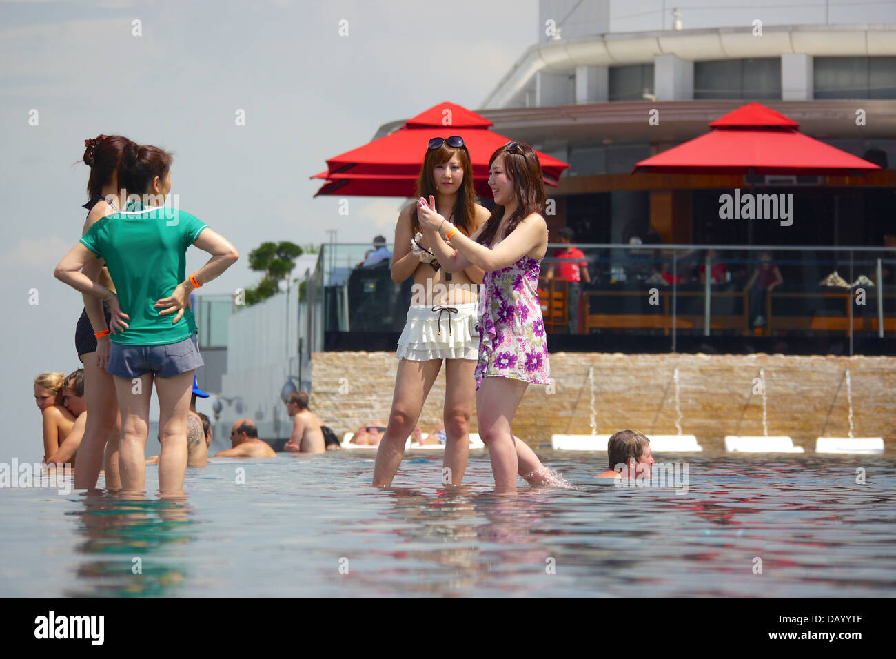 Gli ospiti del Marina Bay Sands godendo un imbibire a posta sul tetto dell'hotel piscina infinity e tenendo le attrazioni di Singapore Foto Stock