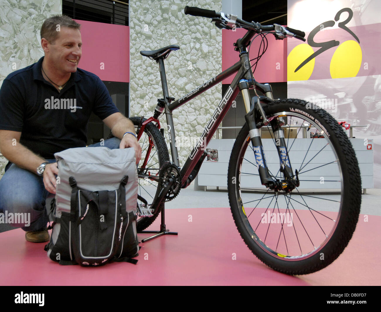Uwe Schlager ginocchia accanto a una mountain bike pieghevole in la foto di  uno zaino a Eurobike 2007 a Friedrichshafen, Germania, 17 agosto 2007. Più  di 800 espositori saranno presenti le biciclette