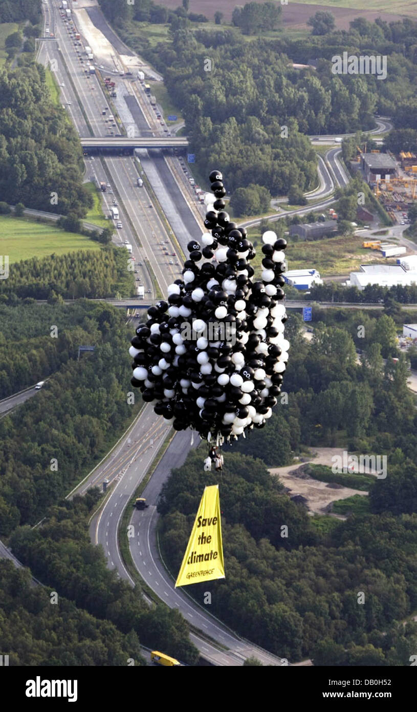 La foto mostra un attivista di Greenpeace battenti con 800 riempito di elio ballons al di sopra di giunzione autostradale Hamburg-Maschen, Amburgo, Germania, 29 agosto 2007. L'attivista vuole dimostrare contro le alte velocità in autostrada tedesca i palloncini neri stampati con "CO2" simboleggiano l'invisibile esalazioni prodotte dalle automobili. Foto: Fred Dott/Greenpeace Foto Stock