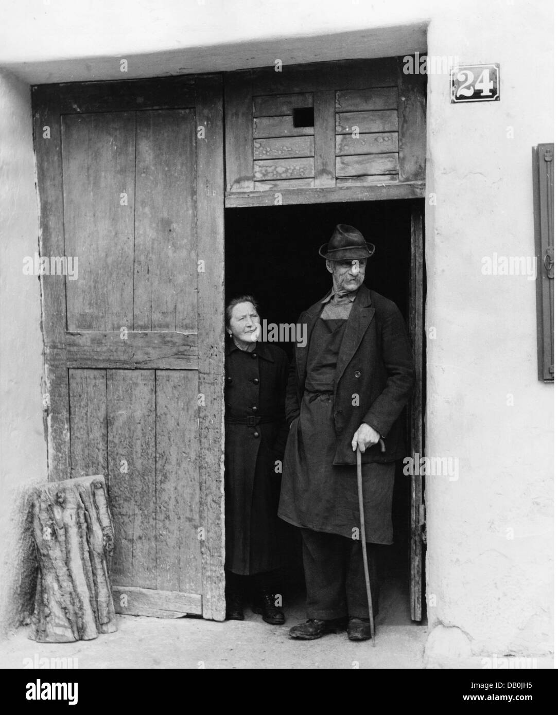 Persone, coppie, coppie anziane, coppie anziane da Mittenwald in piedi in casa ingresso guardando carnevale processione il giovedì grasso, Mittenwald, 1956, Additional-Rights-Clearences-non disponibile Foto Stock