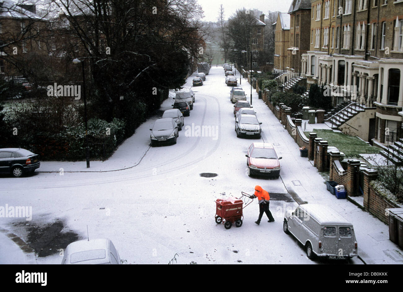 Portalettere consegna post con un carrello in una suburban London street in inverno, Inghilterra Foto Stock