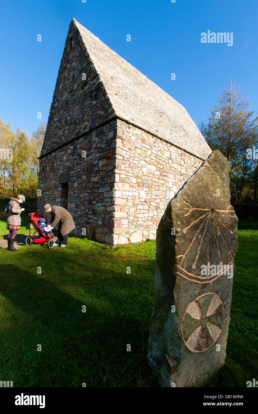 Una famiglia di visitare un monastero cristiano con un orologio solare ricostruita presso l' Irish National Heritage Park a contare Wexford, Irlanda Foto Stock