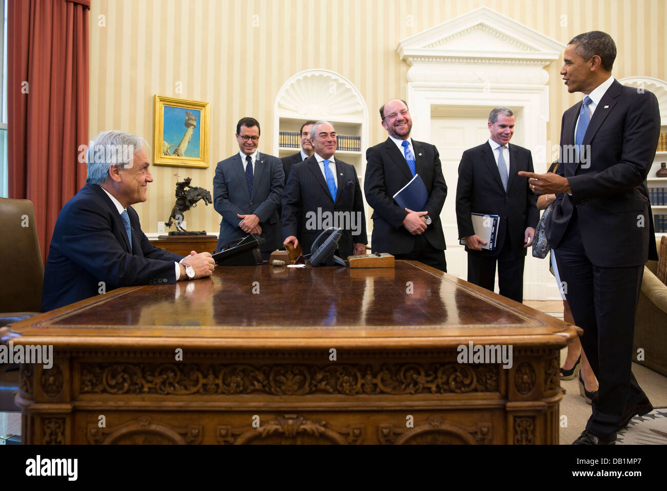 Il Presidente Usa Barack Obama scherza con i membri della delegazione cilena come Presidente Sebastián Piñera del Cile si siede alla scrivania risoluto a seguito di una riunione bilaterale nell'Ufficio Ovale Giugno 4, 2013 a Washington, DC. Foto Stock