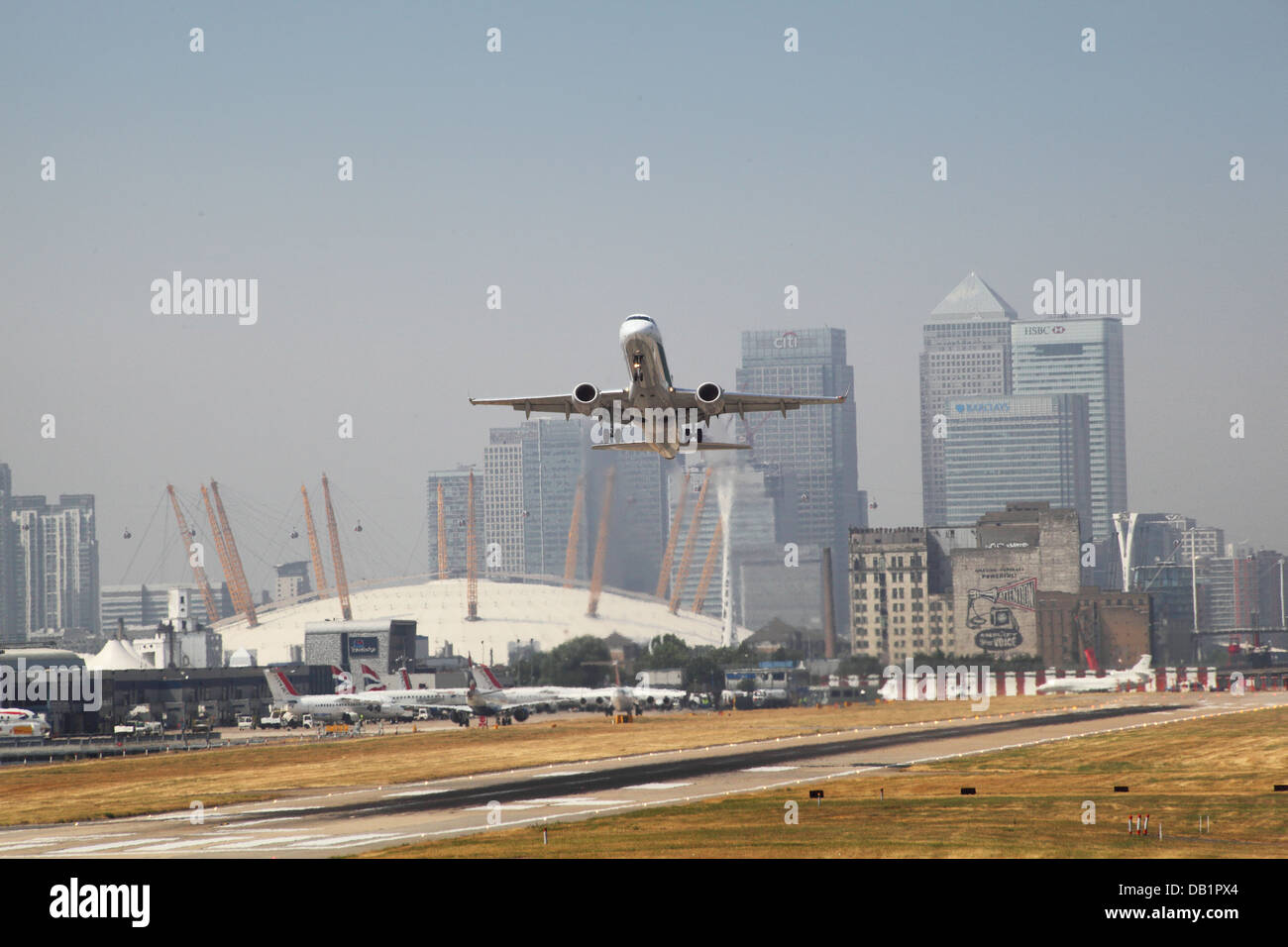 Un passeggero jet decolla dall'Aeroporto di London City con Canary Wharf e il Millennium Dome in background Foto Stock