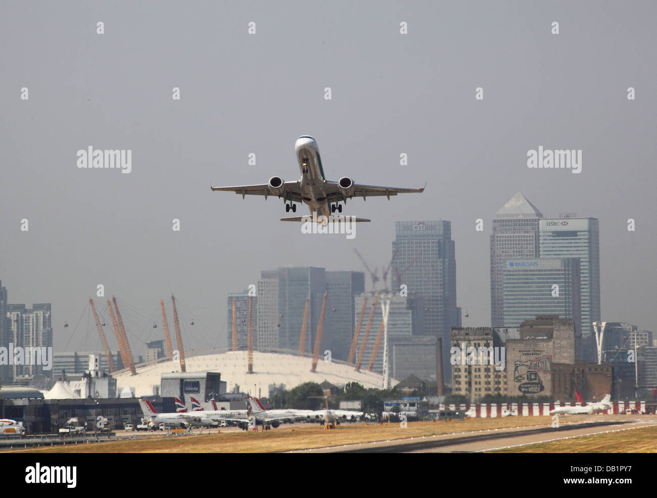 Un passeggero jet decolla dall'Aeroporto di London City con Canary Wharf e il Millennium Dome in background Foto Stock