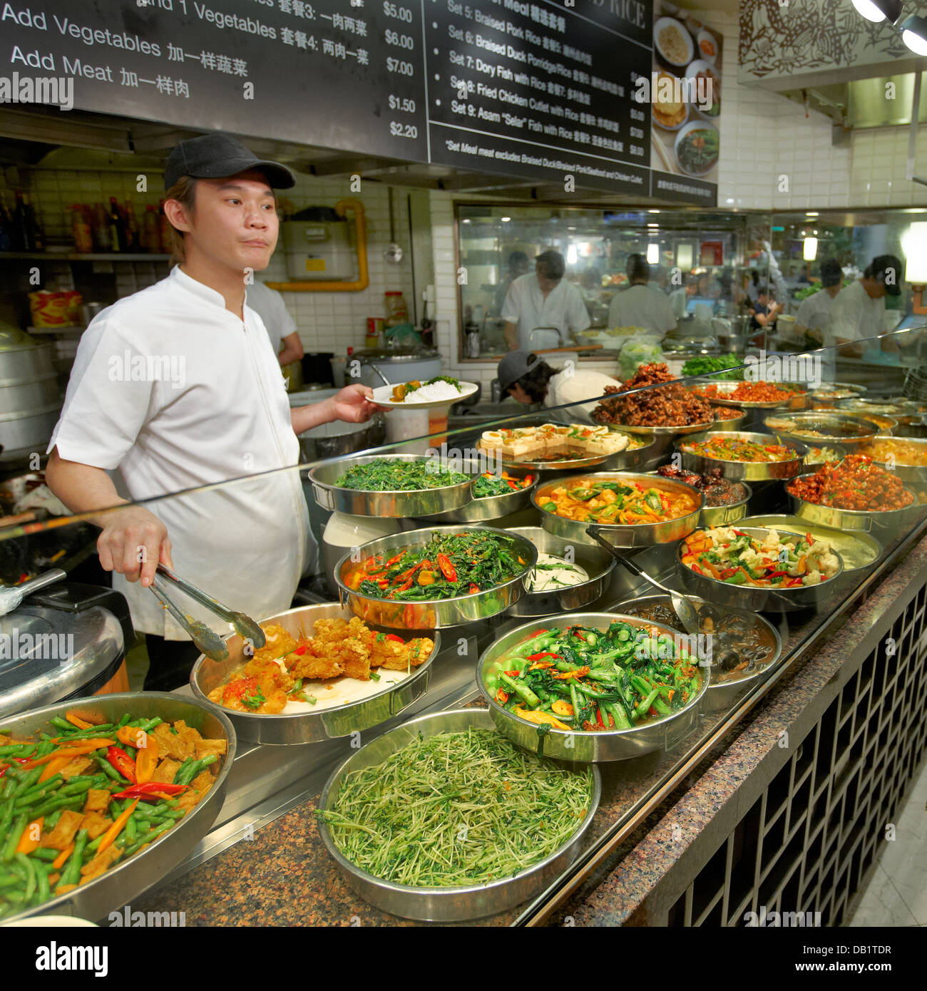 Cameriere in una bancarella di cibo in un centro hawker al coperto. Singapore. Foto Stock