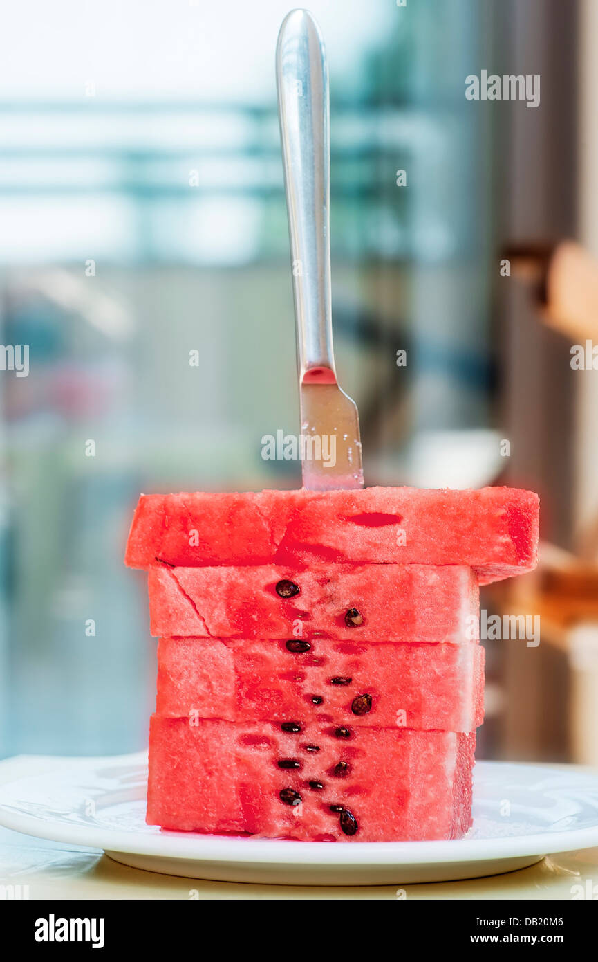 Fette di cocomero vengono impilate su di un piatto d'argento e hanno bloccato un coltello da tavola. Foto Stock