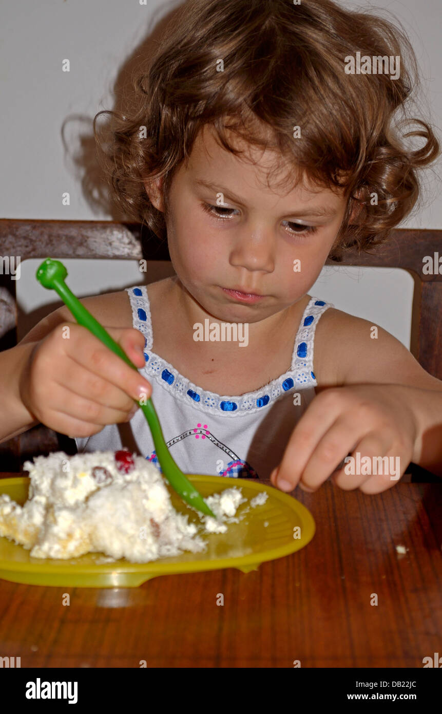 Bambina di 4 anni a mangiare una fetta di torta Foto Stock