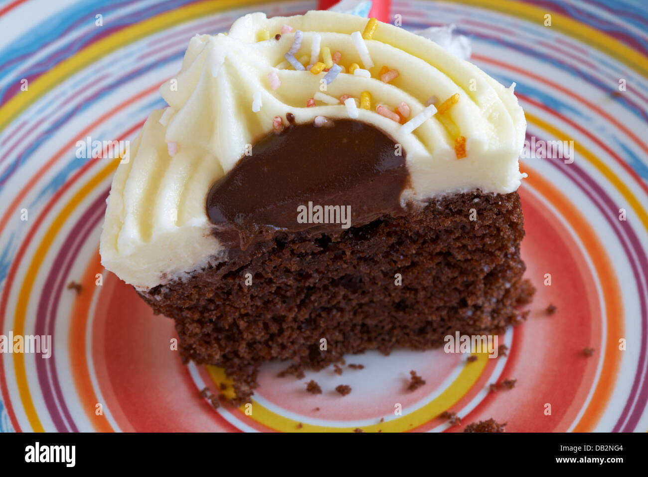 La metà di un The Simpsons 2 D'ohnut Cup cake cupcake impostato sulla piastra colorati - glassa alla vaniglia anello con salsa al cioccolato Foto Stock