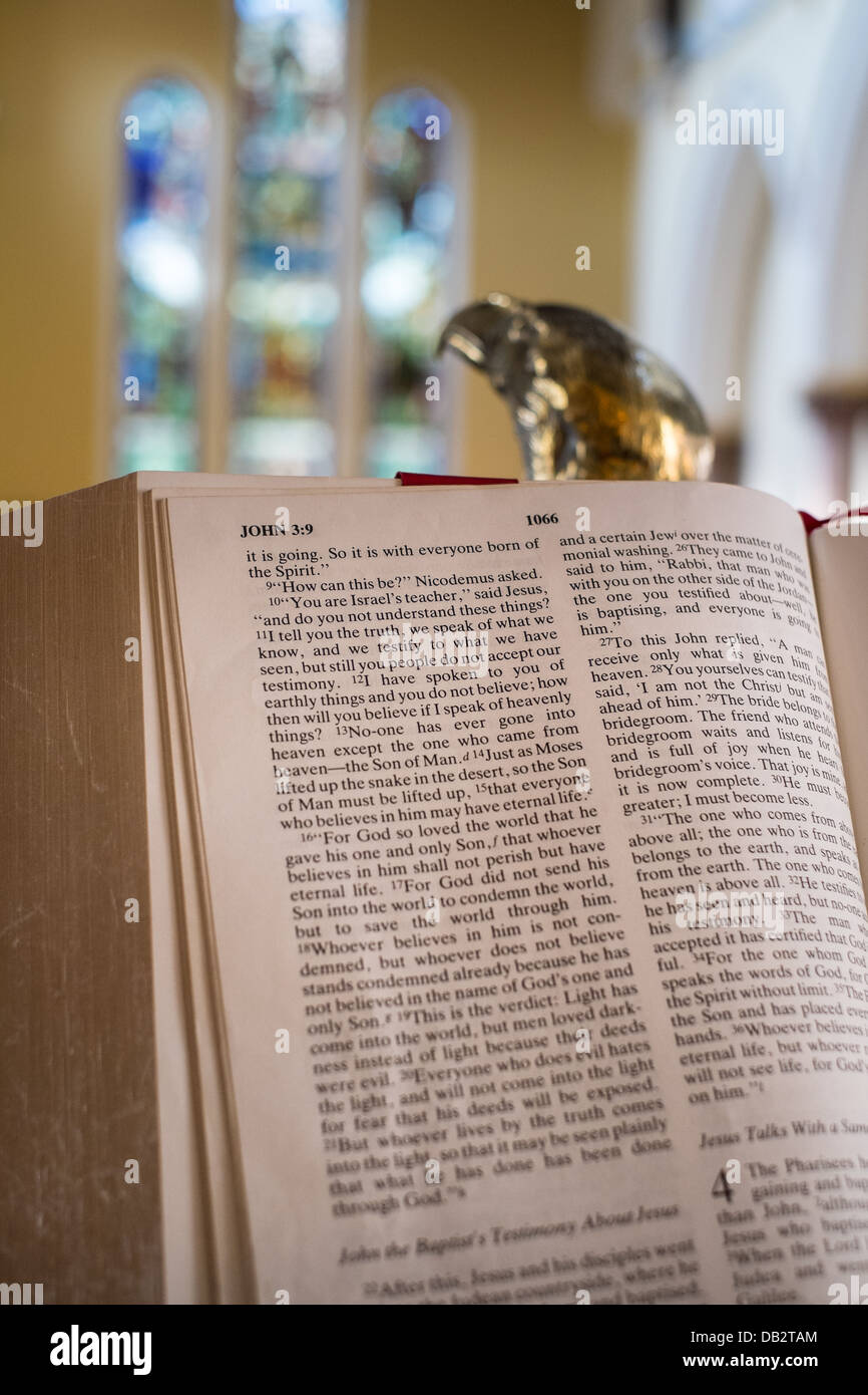 Concetto di immagine della Bibbia, aperto presso il St John 3.16, appoggiato sulla lettura eagle leggio con finestre di vetro macchiate in background. Foto Stock