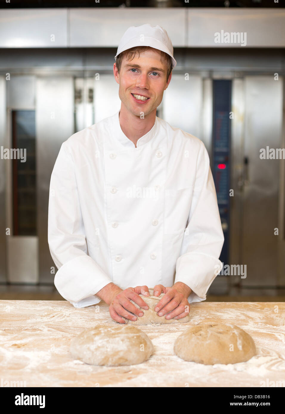 Baker impastare la pasta di pane in bakehouse della panetteria Foto Stock