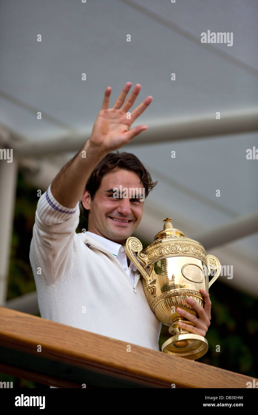 Roger Federer sorge su i membri balcone e mostra il trofeo per la folla fuori dal centro Corte i campionati di Wimbledon Foto Stock