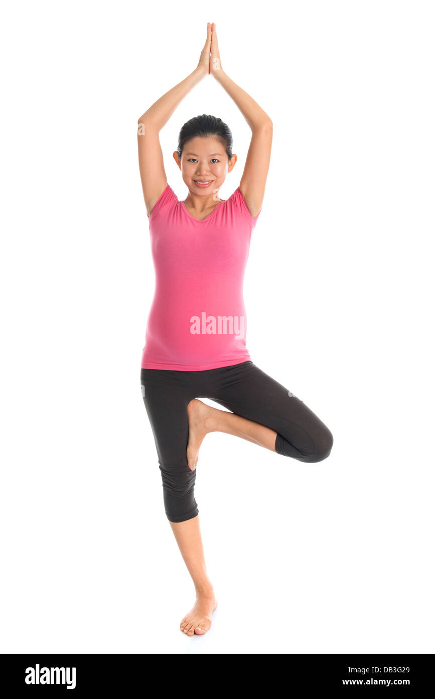 Yoga prenatale. Lunghezza completa asiatici sano donna incinta facendo esercizi yoga stretching a casa, fullbody isolati su sfondo bianco. Posizioni di yoga in piedi la posizione dell'albero. Foto Stock