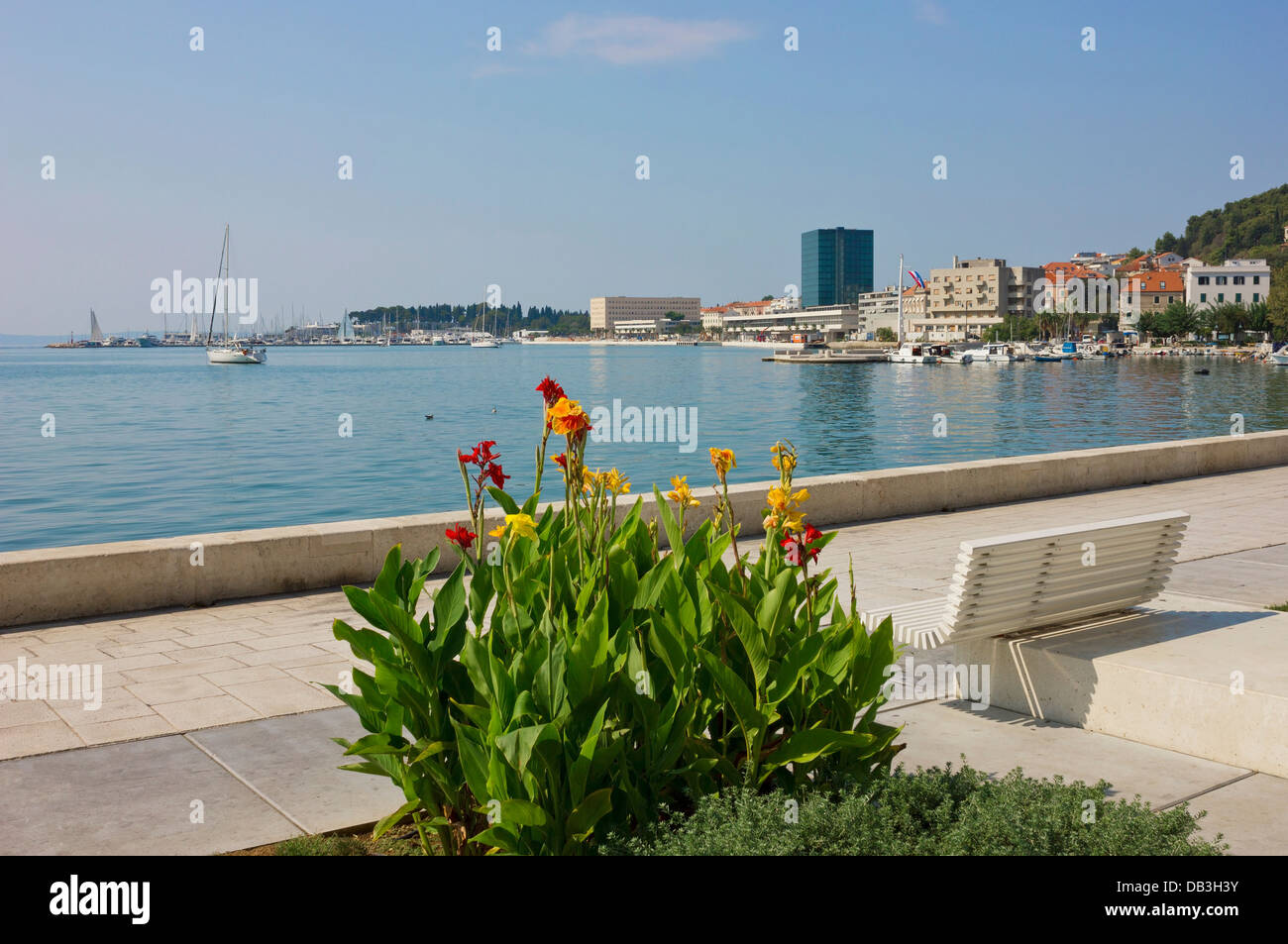 Vista panoramica del lungomare di Riva in Split, Croazia con fiori colorati, una panca e barche a vela in marina. Foto Stock