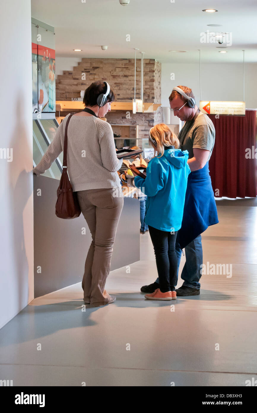 Famiglia di turisti tаке audio guida durante il tour in fabbrica di formaggio, Stein regione Appenzell, Svizzera Foto Stock