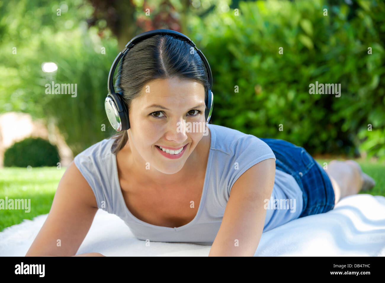 Donna con cuffie in parco pubblico sulla coperta Foto Stock