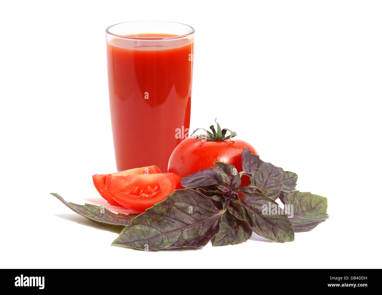 Pomodori freschi, rosso basilico e bicchiere pieno di succo di pomodoro Foto Stock