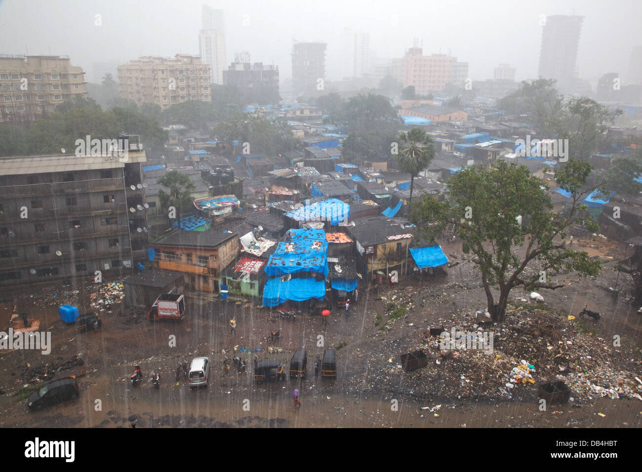 Una vista su una delle baraccopoli con un alto-aumento appartamento residenziale edifici in background durante una pioggia monsonica in Mumbai Foto Stock