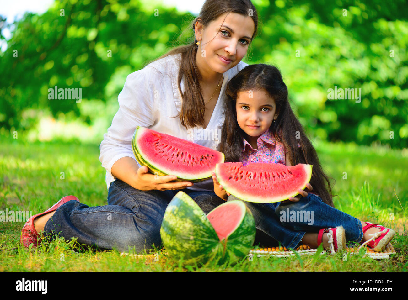 Felice famiglia indiana mangiando anguria in posizione di parcheggio Foto Stock