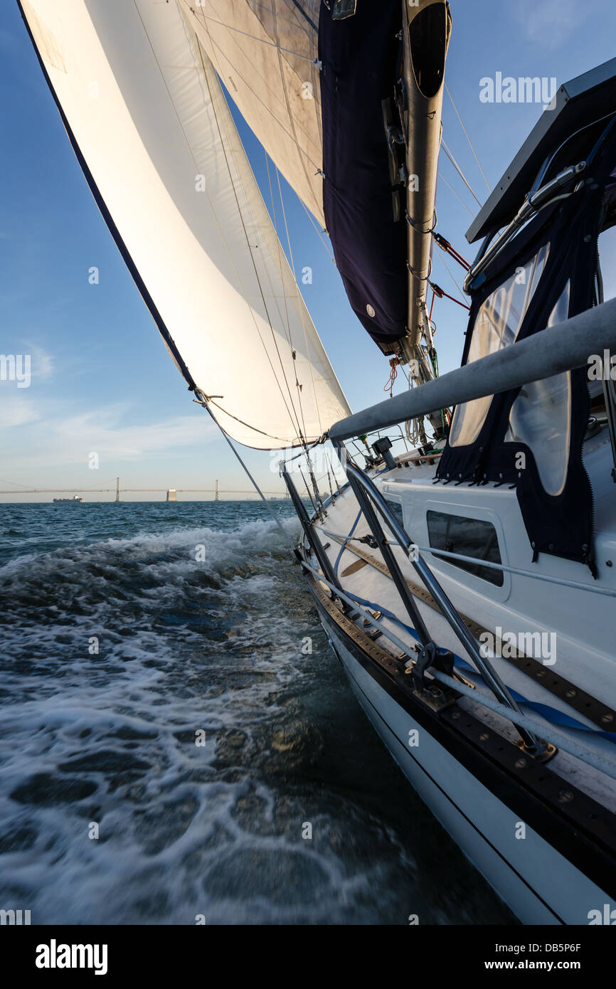 Verticale, vista laterale ravvicinata del racing in barca a vela come teste per il Ponte della Baia di San Francisco Bay in una giornata di sole Foto Stock