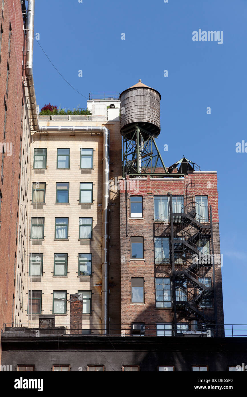 Edifici di appartamenti con il fuoco sfugge e serbatoio sul tetto nella città di New York Foto Stock