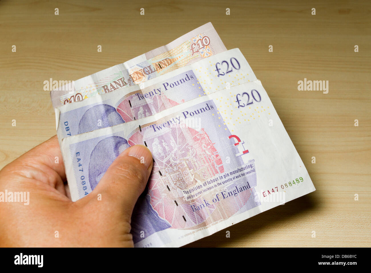 Un mans tenere in mano 50 sterline in contanti, costituito da 2 € 20 e 1 £10 pound note, England, Regno Unito Foto Stock