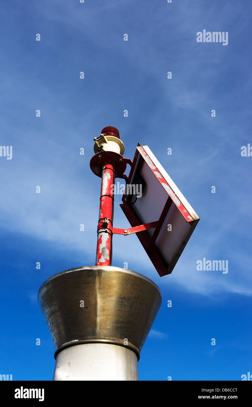 Piccolo faro con lampadina rossa e pannello solare Foto Stock