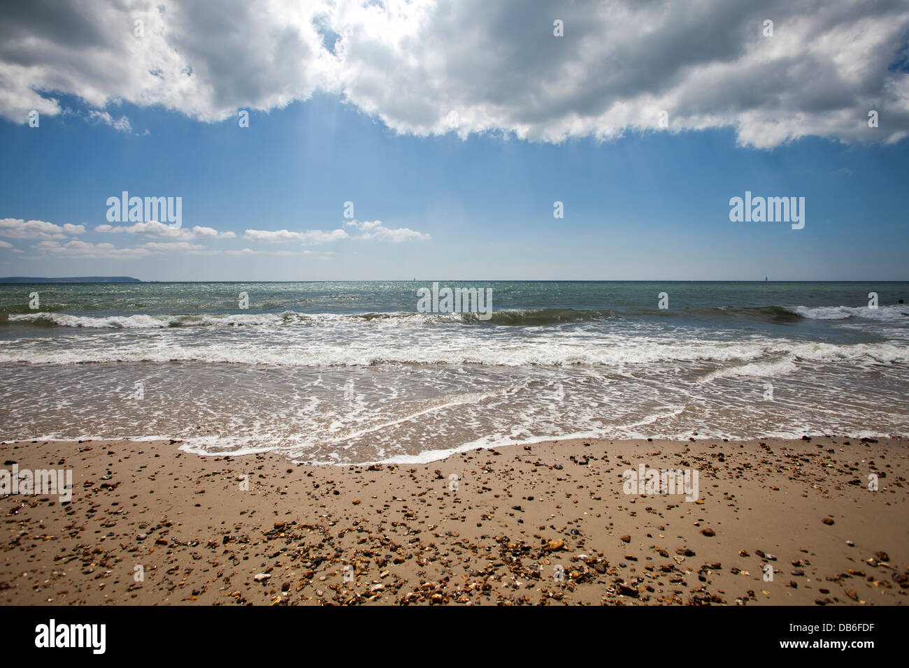 Un filamento di vuoto di spiaggia con delicata navigare sotto le nuvole illuminate dal sole Foto Stock