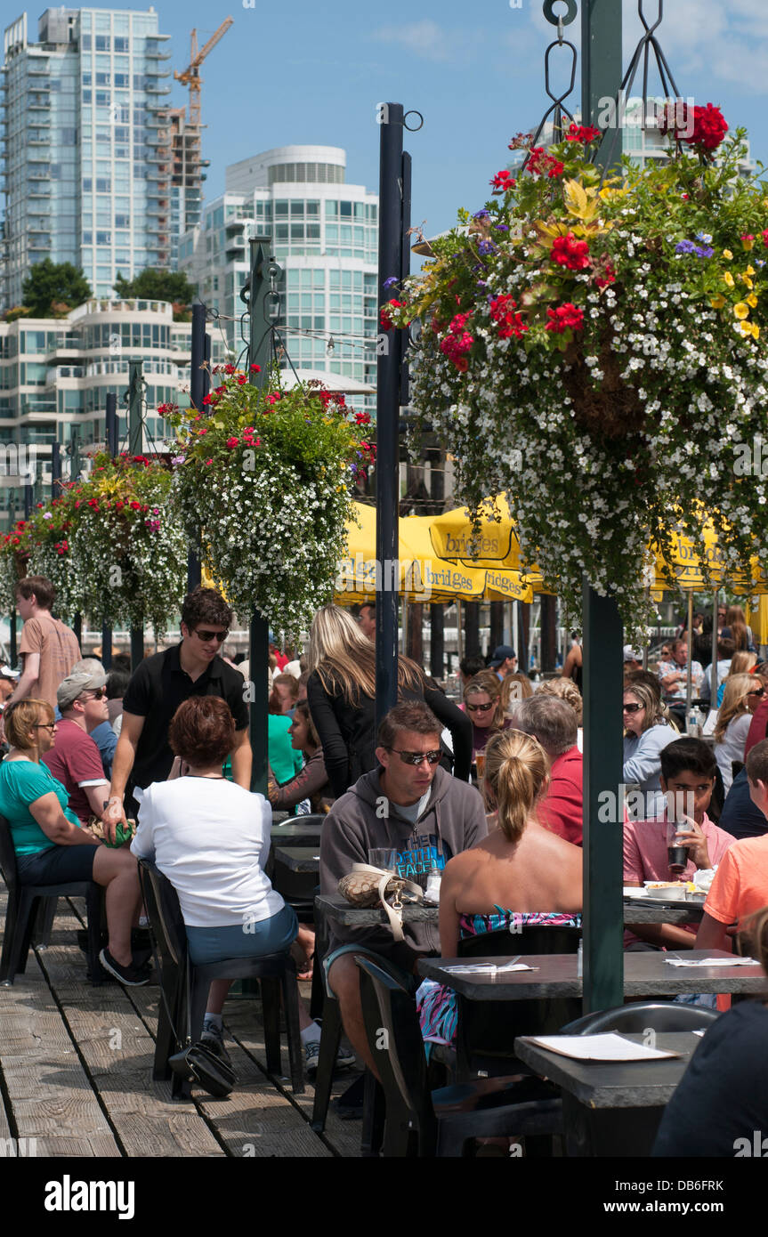 Le persone sedute a tavoli all aperto a ponti Ristorante che approvvigiona a sala da pranzo esterna su Granville Island, Vancouver, British Columbia. Foto Stock