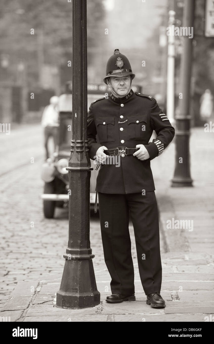 Un poliziotto dall'epoca edoardiana o 1910's periodo appoggiato su di un lampione Foto Stock
