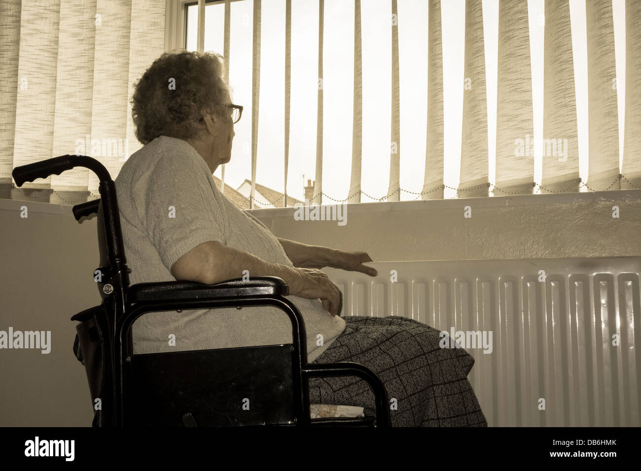 Donna di novanta anni con mano sul radiatore che guarda fuori dalla finestra. REGNO UNITO. Coronavirus, autoisolamento, distanza sociale, quarantena... concetto Foto Stock