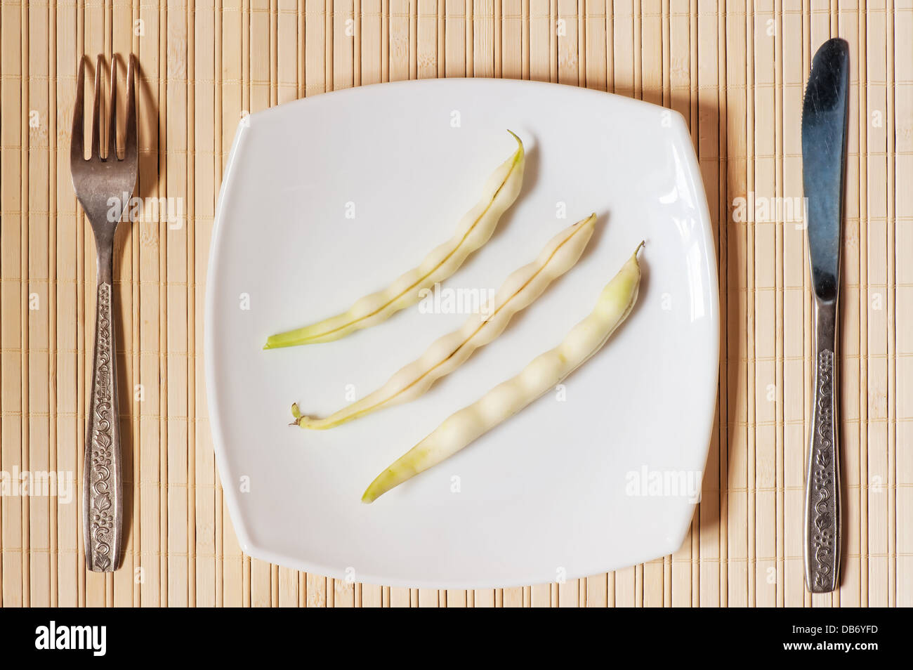 Tre baccelli di fagioli su un quadrato bianco piastra. Foto Stock