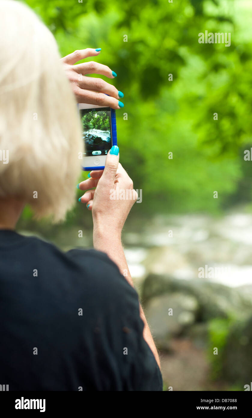 Signora fotografare un paesaggio con cellulare fotocamera, vista da dietro Foto Stock