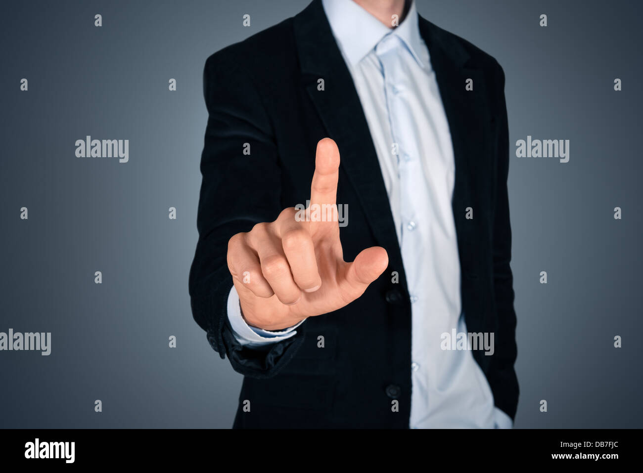 Ritratto di bello imprenditore toccando un vuoto nella schermata invisibile. Touch screen Concetto di immagine. Isolato su sfondo scuro Foto Stock