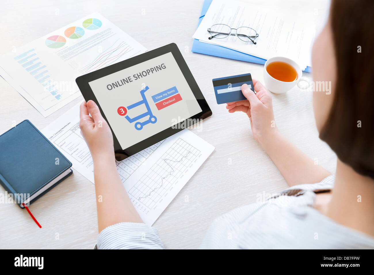 Imprenditrice caucasica seduto alla scrivania in ufficio e utilizzando la carta di credito e moderna tavoletta digitale per lo shopping online Foto Stock