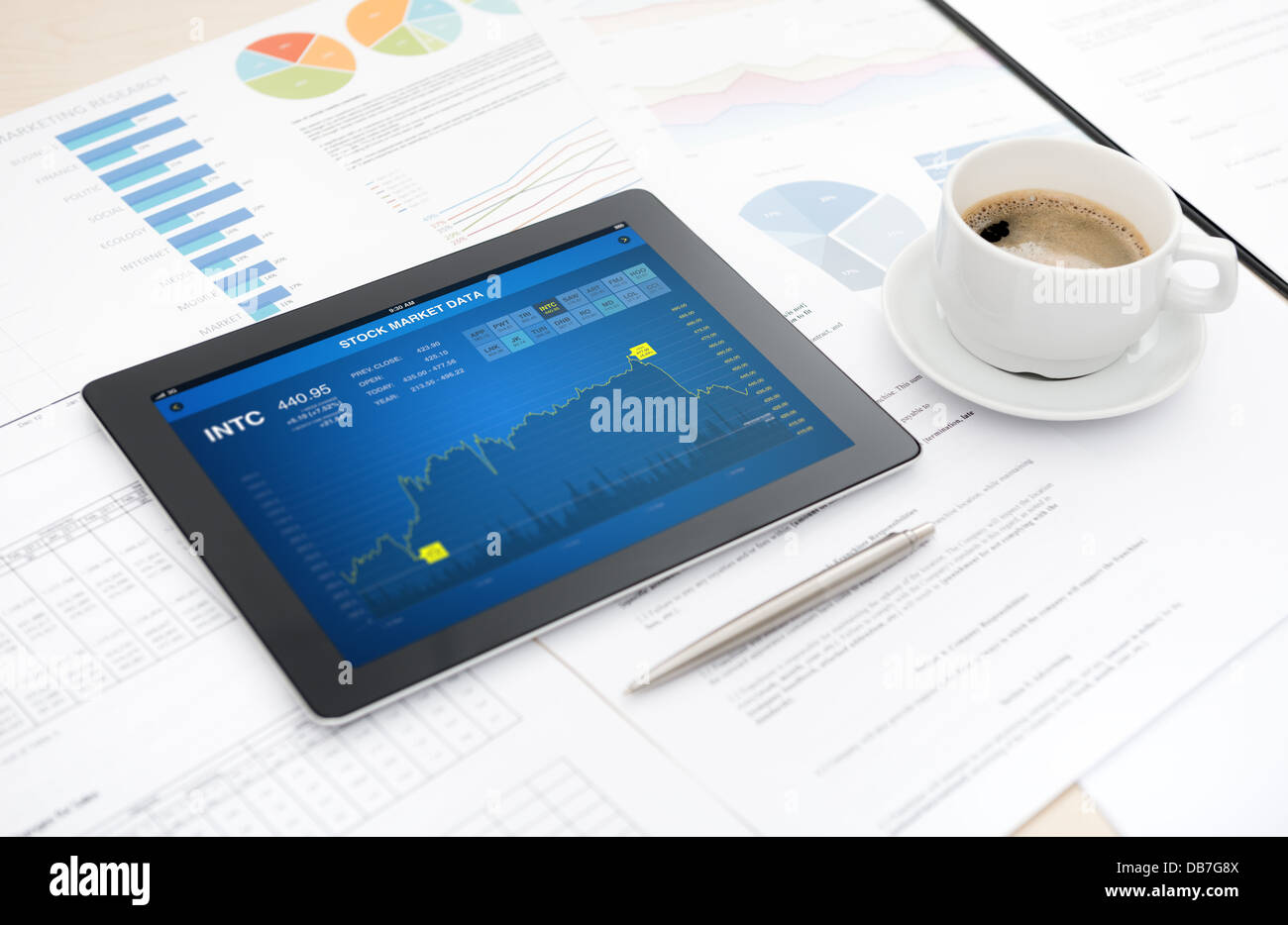 Moderna tavoletta digitale con dati sulla borsa applicazione su una scrivania con alcune carte e documenti, penna e una tazza di caffè Foto Stock