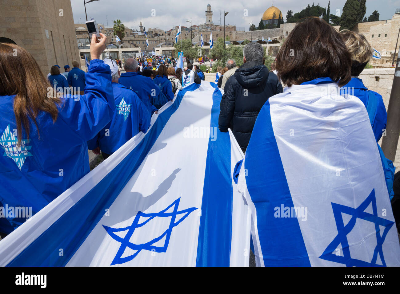 Folla in marcia con una lunga bandiera israeliana intorno alle mura della citta'. Gerusalemme la città vecchia. Israele. Foto Stock