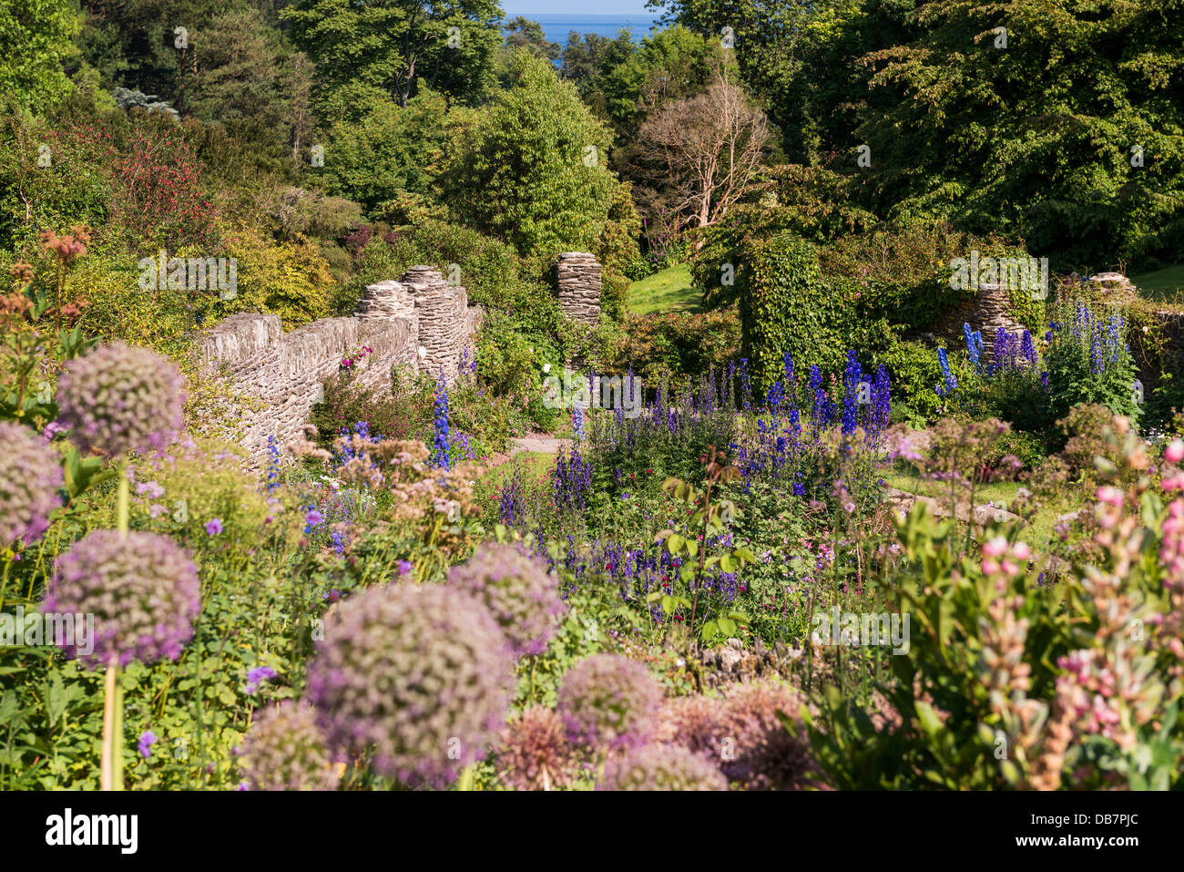 Kingswear, Devon, Inghilterra. 9 luglio 2013. Un giardino in scena con il mare in lontananza attraverso gli alberi. Foto Stock