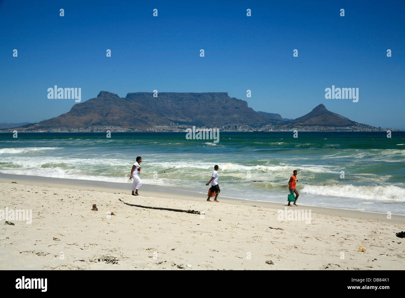 La gente a piedi su Blaauwberg Beach a Cape town, Sud Africa con Table Bay e il Monte Table e la Lions Head sullo sfondo. Foto Stock