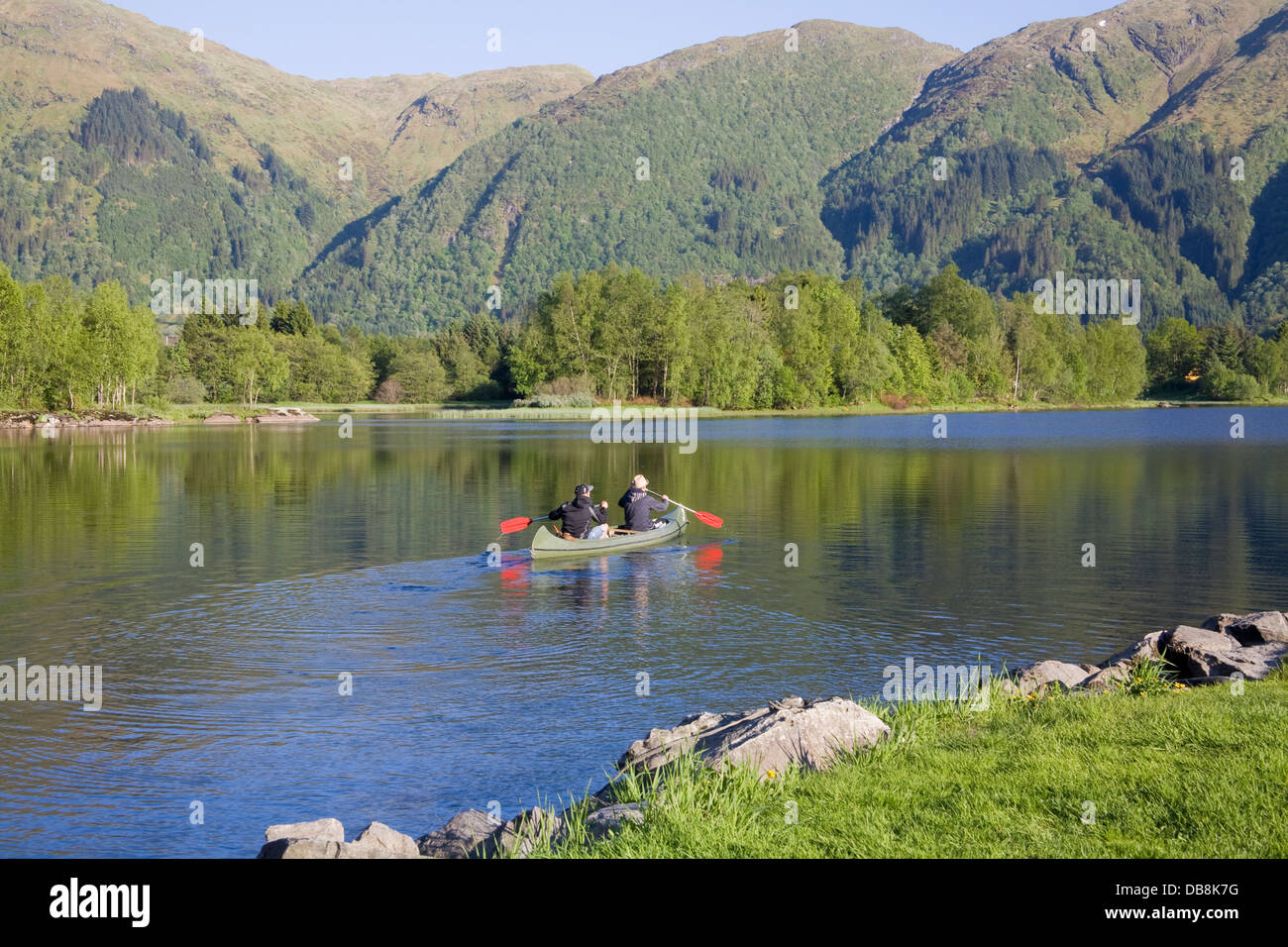 Haukeland Norvegia Europa due giovani uomini paddling a noleggio una canoa in tutta calma Haukeland Lago Foto Stock