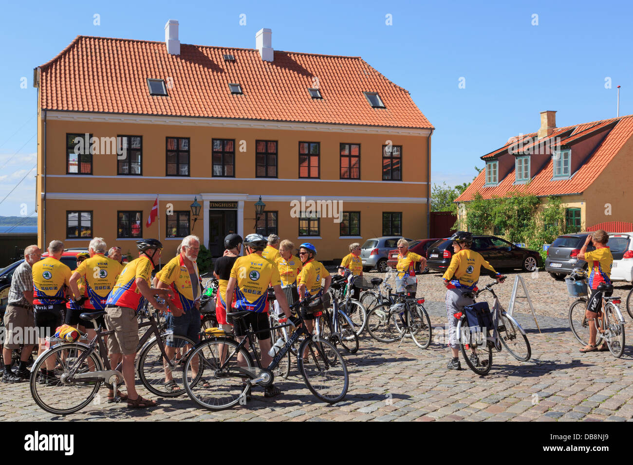 Ciclismo club di ciclisti senior con le biciclette da arte della società Tinghuset Courthouse in città in ciottoli square a Ebeltoft Danimarca Foto Stock