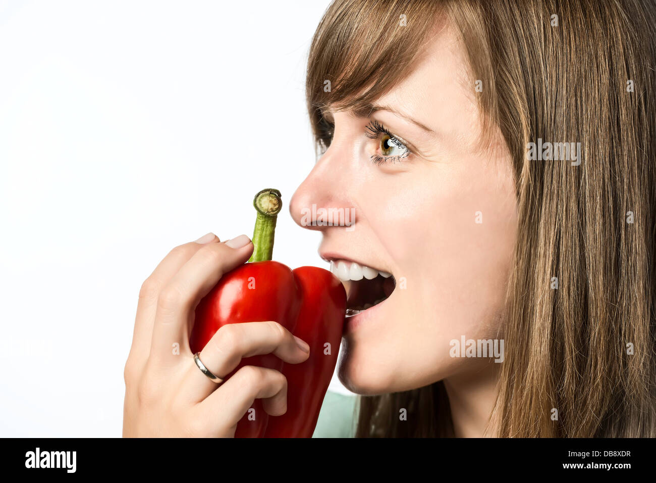 Giovane bella donna aggredendo un peperone rosso, isolato su sfondo bianco Foto Stock